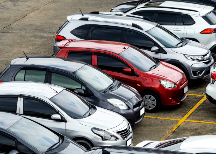 Multiple cars red black silver parked in parking lot.