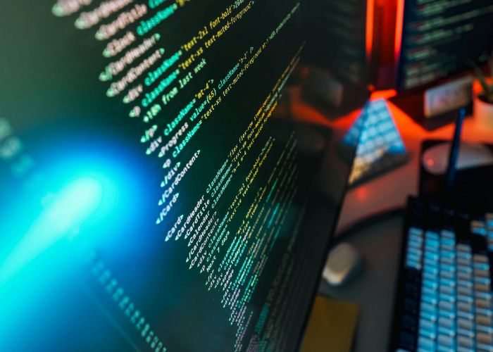 multicolor coding text on computer screen on desk with keyboard.