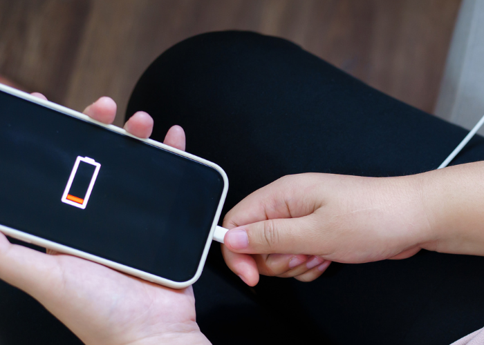 Hand plugging in iphone with a dead battery.