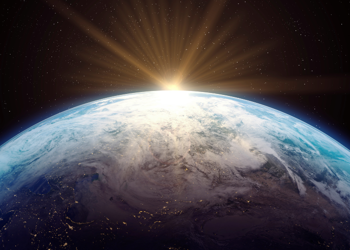 Sun and beam rising over aerial view of earth in space.