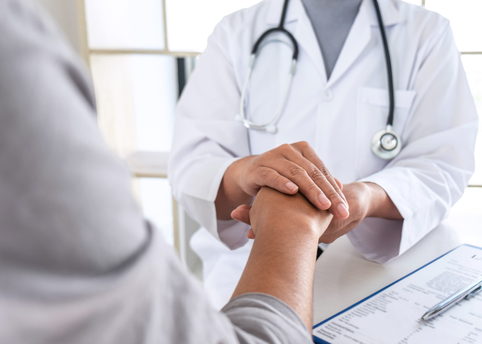 Doctor holding patients hand while wearing lab coat.