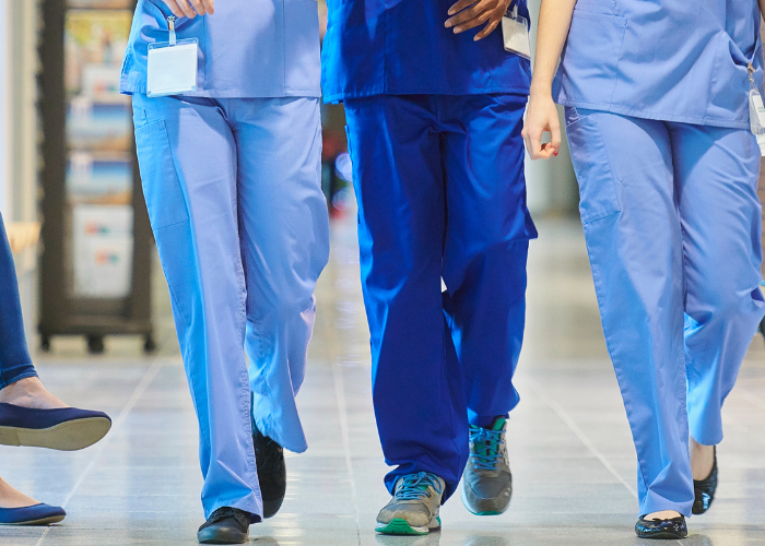 Nurses walking down hall in blue scrubs.