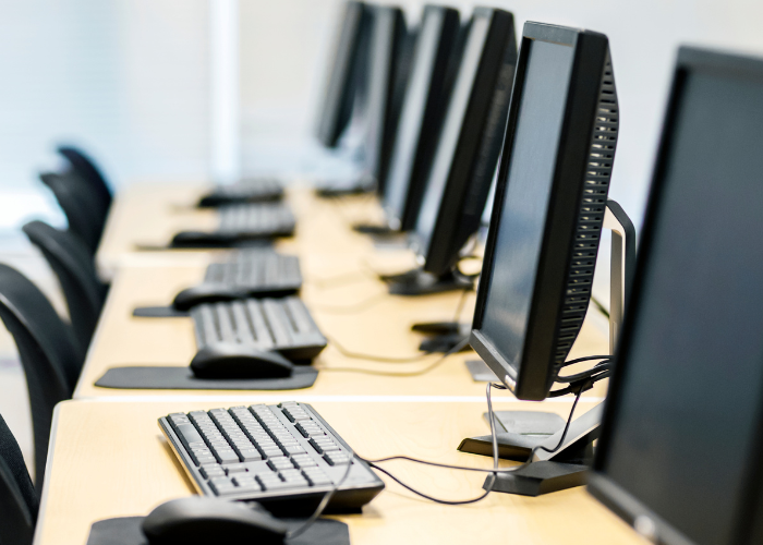 Computers line up on desk with mouses keyboards.