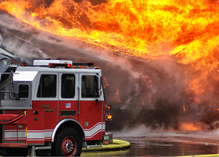 Fire truck in front of large blazing fire.
