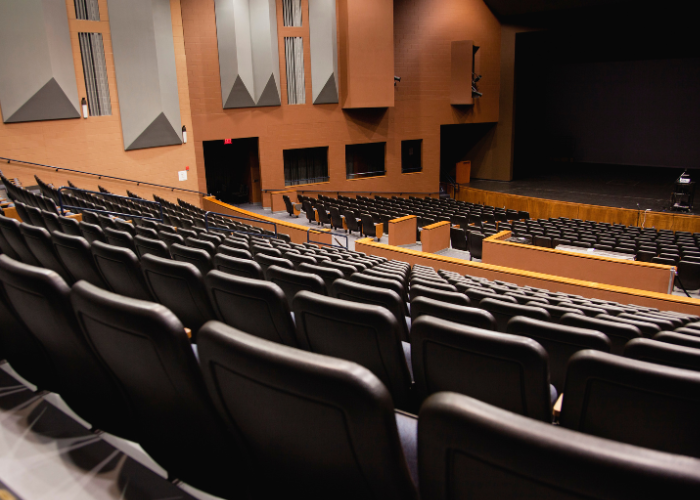 Empty auditorium with black chairs.