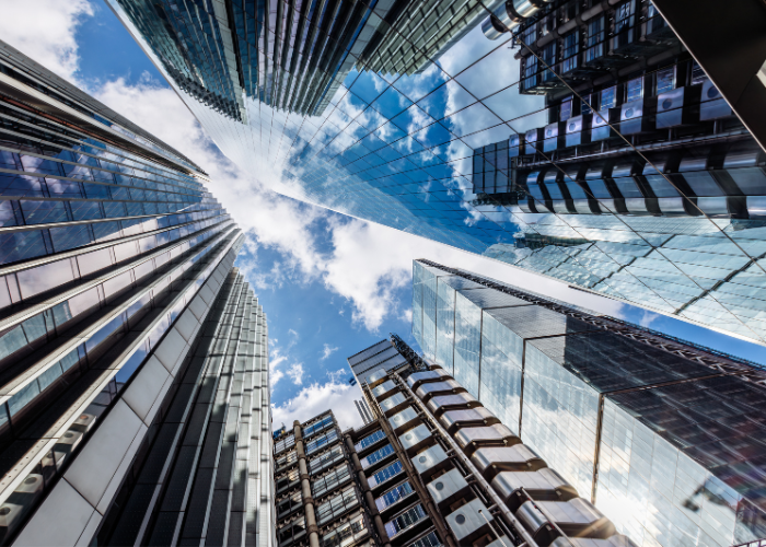 Metallic chrome skyscrapers with bright blue sky and clouds.
