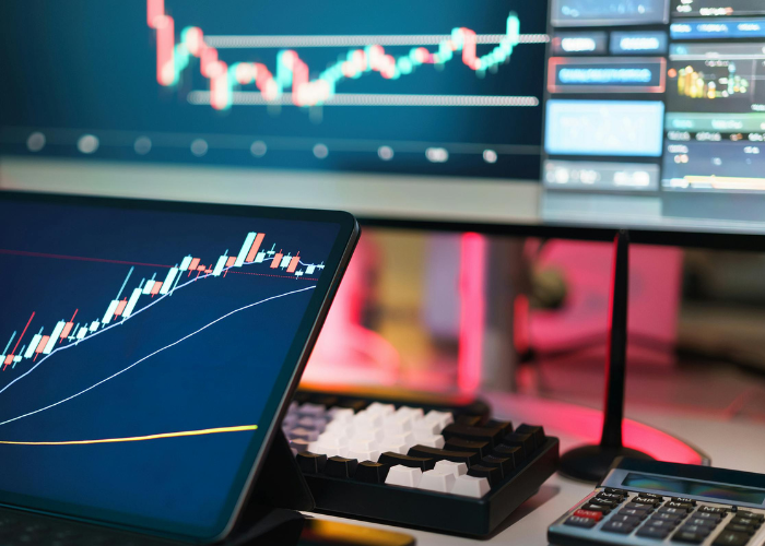 Technology for finance job. Calculator next to computer with graphs.