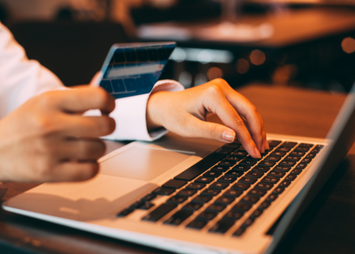 Hands typing in credit card information onto computer for online shopping purchase.
