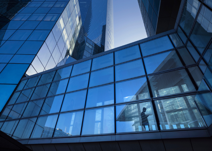 Person walking through skyscraper with glass windows.
