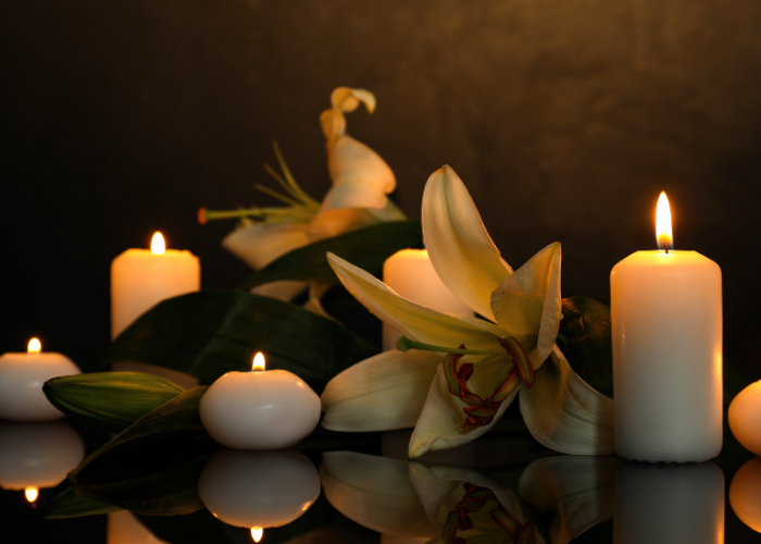 White lily flowers surrounded by lit candles.