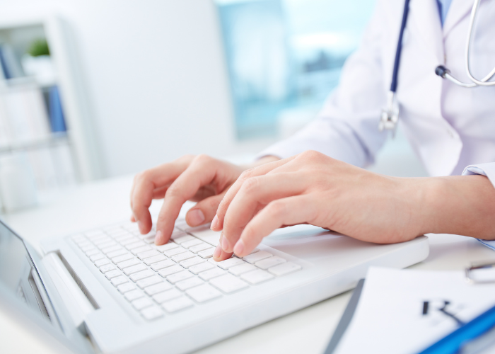 doctor typing medical records into computer.