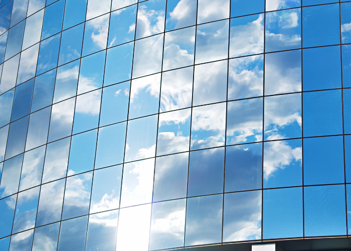 Reflection of white clouds, blue sky, and sunlight in windows.