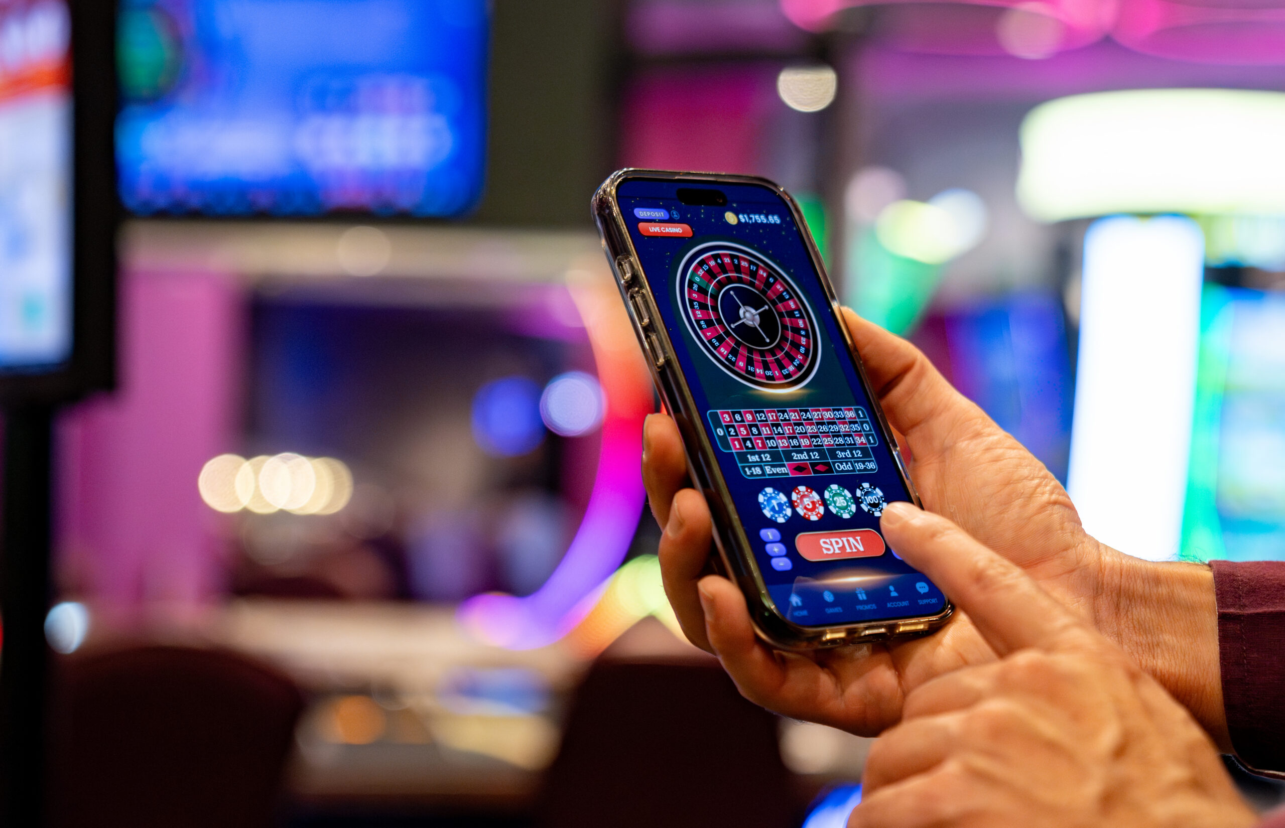 Close-up on a person playing the roulette on a cell phone at a casino to represent online social casinos