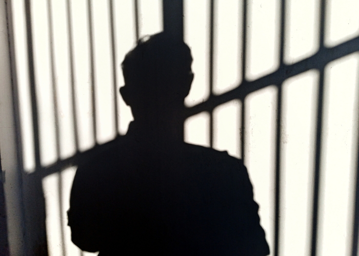Silhouette of person in front of prison bars